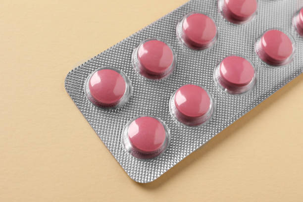 istock Pink pills in blister on beige background, closeup 1634382079