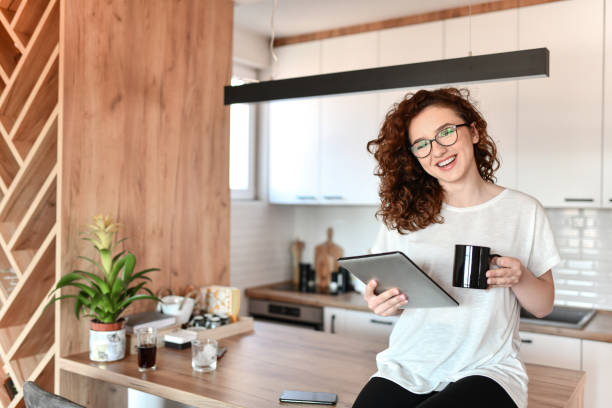 istock Smiling Female Starting Work Day From Home With Digital Tablet And Coffee In Hand 1634383668