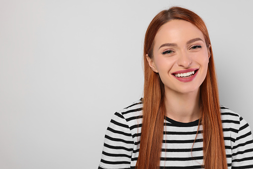 Portrait of beautiful young woman on light gray background, space for text