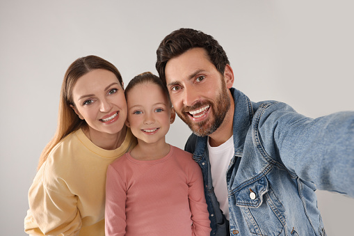 Happy family taking selfie on light grey background