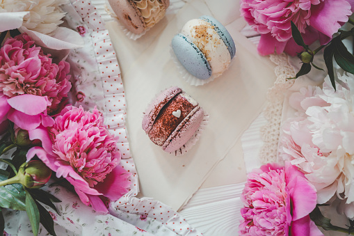 Macaroons and peonies, flat lay top view.