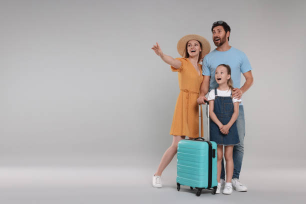 istock Happy family with turquoise suitcase on light grey background. Space for text 1634431349