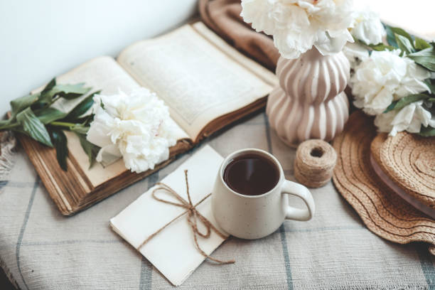 istock Cup of tea, straw hat, open book and peonies, spring still life 1634437752