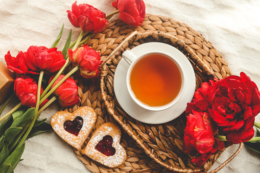 Bandeja con sabroso desayuno, ramo de peonías y regalo para San Valentín en la cama photo