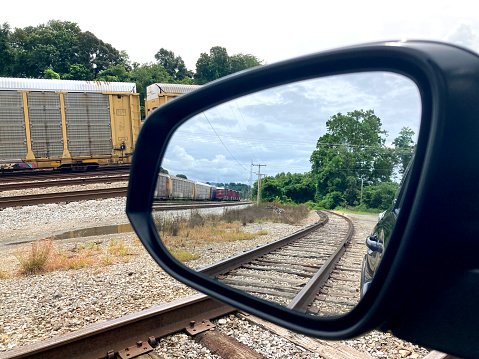 View of train yard through a car's side mirror.