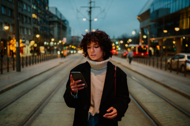 istock Curly girl holding her smart phone while waiting at the train station. 1634694930