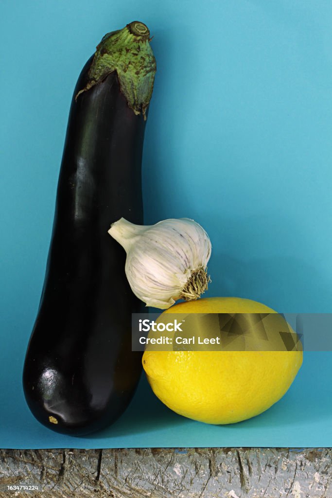 Eggplant and things that go with it Eggplant garlic and lemon on a light blue background Color Image Stock Photo