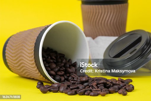 istock Paper cups with coffee beans on yellow background 1634741808