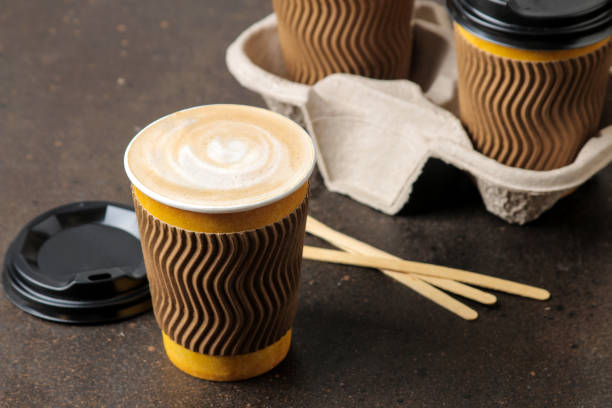 istock Paper cups with cappuccino on a stand on a brown table. coffee to go 1634741816