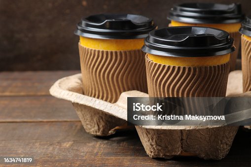 istock Paper cups with coffee on a stand on a brown table 1634741819