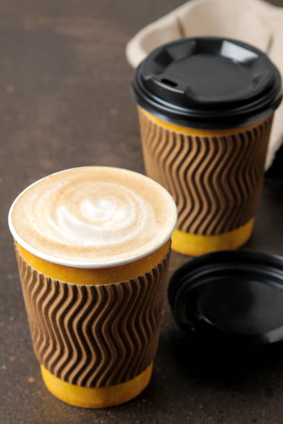 istock Paper cups with cappuccino on a stand on a brown table. coffee to go 1634741825