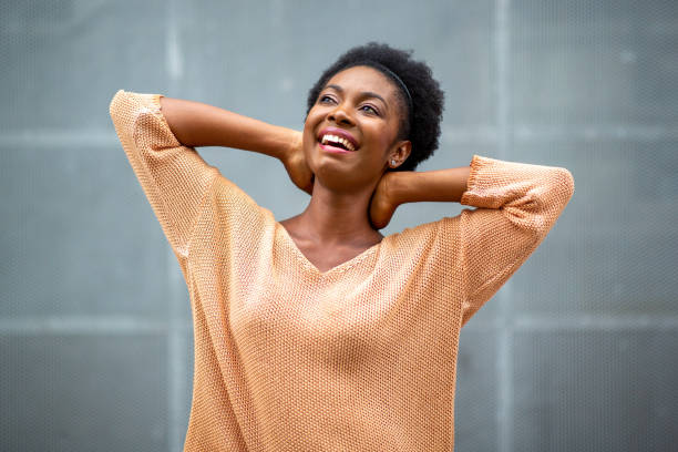 istock happy young black woman with hands behind head looking away 1634747045
