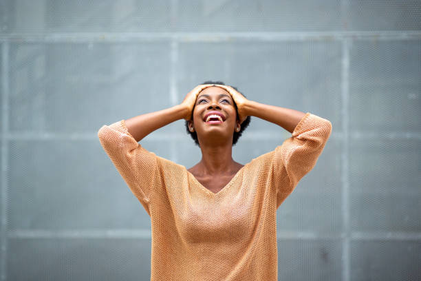 istock cheerful young black woman with hands on head and looking up 1634747183