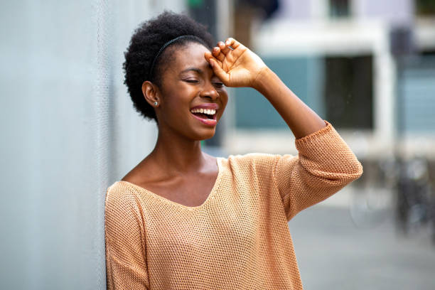 istock young black woman leaning against wall laughing outside 1634747185