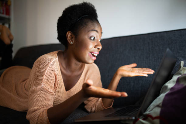 istock young black woman lying on couch with laptop computer 1634747762