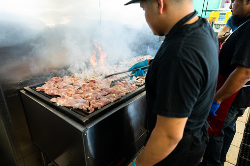 Still shot of chicken being grilled inside a Mexican restaurant during the day.