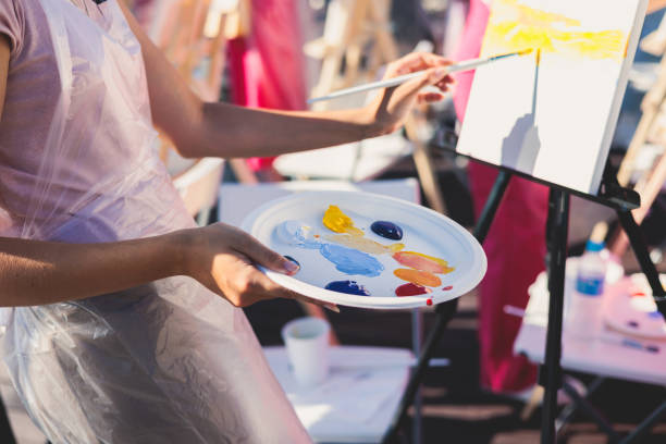 istock Process of drawing, group class of talented students with painting easels and canvases during lesson of watercolour painting outdoors, drawing class 1634807035