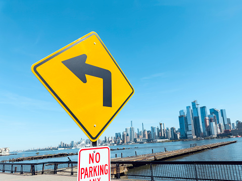 Road sign with left turn arrow showing the opposite of New York City