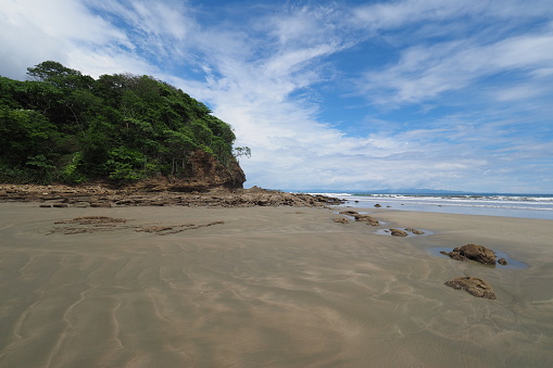 Beach and rocks of Playa Hermosa on the Pacific coast of Nicaragua, Central America on sunny summer afternoon.
