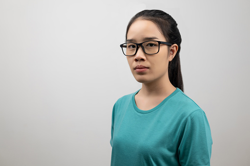 Portrait of young Asian woman patients neurocrine disease in green t-shirt on light gray background, classic congenital adrenal hyperplasia, rare hormonal disorders, nervous system medical concept