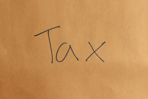 Brown envelope paper with word tax wrote on it. Annual revenue and income tax time concept.