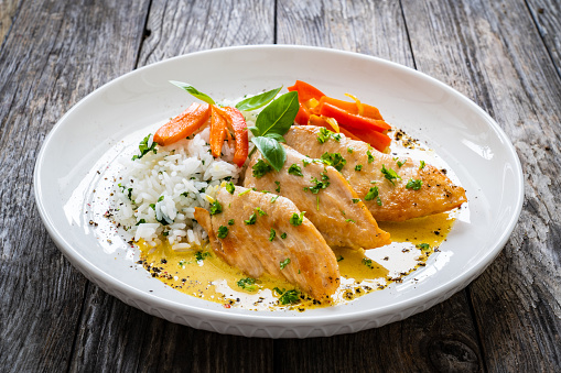 Stir-fried chicken meat, white rice and vegetables on wooden table