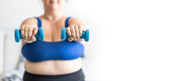 Close-up view of fat woman holding dumbbells. Woman diet weight loss overweight problem concept.