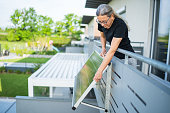 woman adjusting solar panel on balcony house