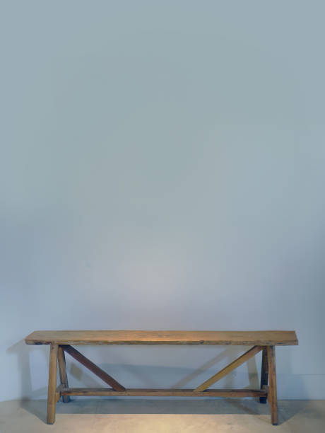 istock An empty blue grey color wall with a wooden bench against the wall, spotted lighting from above, empty space for copy or text insert, graphic resource 1635118838