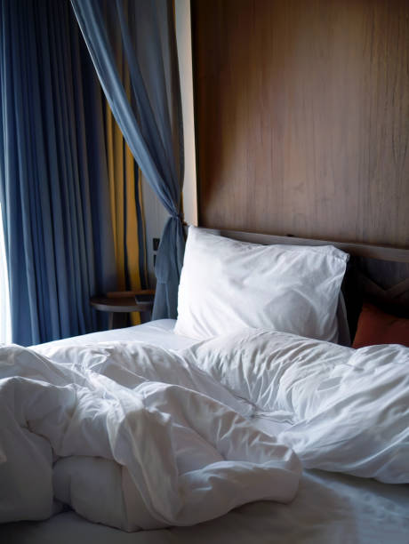istock Crumpled white bedding sheets linen with pillow and blanket in soft morning lights, comfortable mood of rest and relax bedroom, unmade empty bed hotel business concept, messy 1635119361