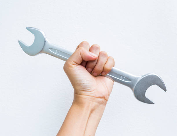 istock Hand holding double open end wrench on white cement wall background 1635130238