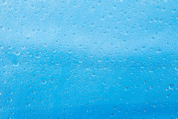istock Rain drop on at glass window over blue sky background 1635132693