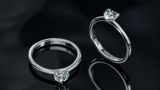 istock Two platinum diamond rings sits on a shiny black glass surface. heart shaped diamond rings design with 3d render. 1635144825
