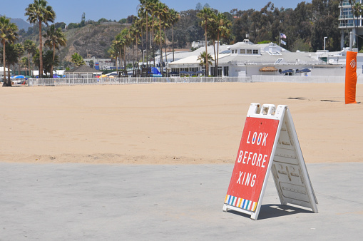 ped xing sign in a red background, sign on the sand, on the beach, look before xing sign