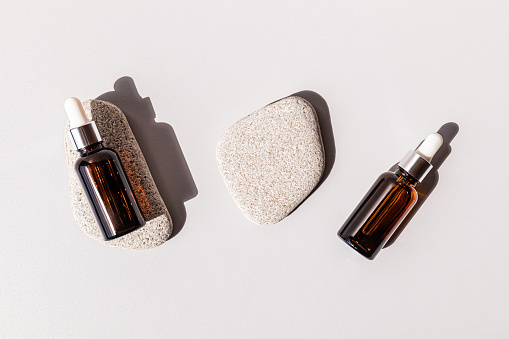 Natural cosmetics in two bottles with a pipette lying on oval flat gray stones. A copy of the space. Design branding. empty packaging