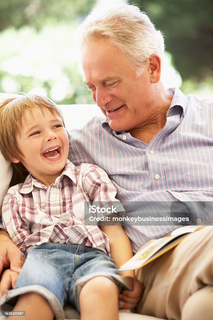 Дед и Внук читать вместе на диване - Стоковые фото Прародитель роялти-фри