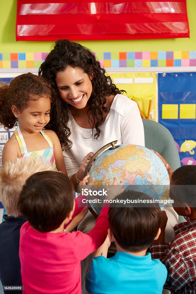 Elementary Age Schoolchildren In Geography Class With Teacher Group Of Elementary Age Schoolchildren In Geography Class With Teacher Looking At Globe Teacher Stock Photo