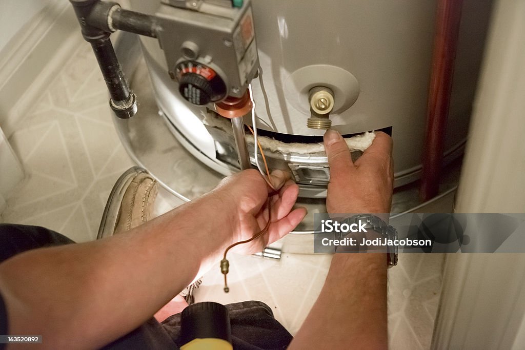 Man shines flashlight on hot water heater A man uses a flashlight to help him see the hot water heater in a dark closet Boiler Stock Photo