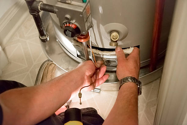 Man shines flashlight on hot water heater stock photo