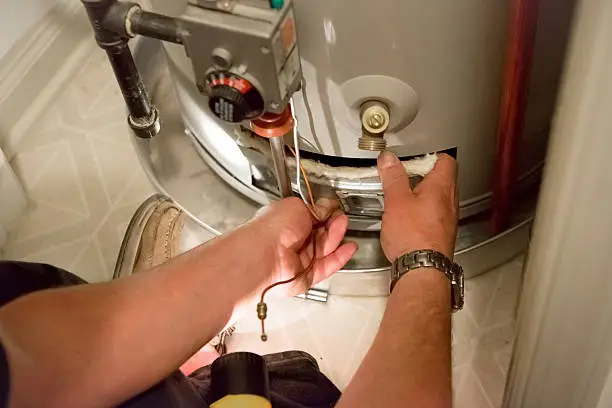 Photo of Man shines flashlight on hot water heater