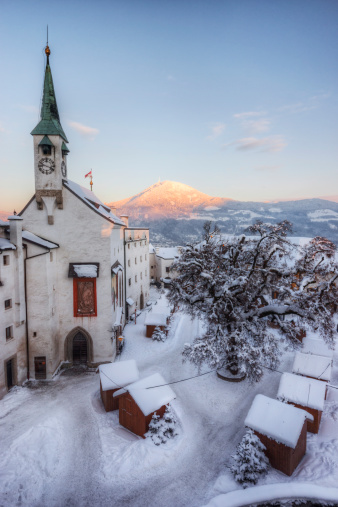 Sunset as seen from within the castle walls of the Hohensalzburg Fortress during the Christmas season. Small sheds for the traditional Christmas Market (Weihnachtsmarkt) can be seen below, with the last light of day cast upon Gaisberg mountain in the distance.