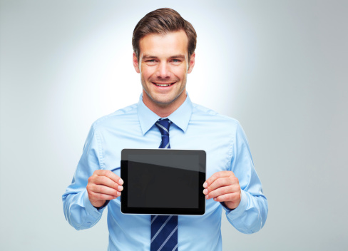Studio portrait of a young businessman holding a digital tablet in front of his midsection