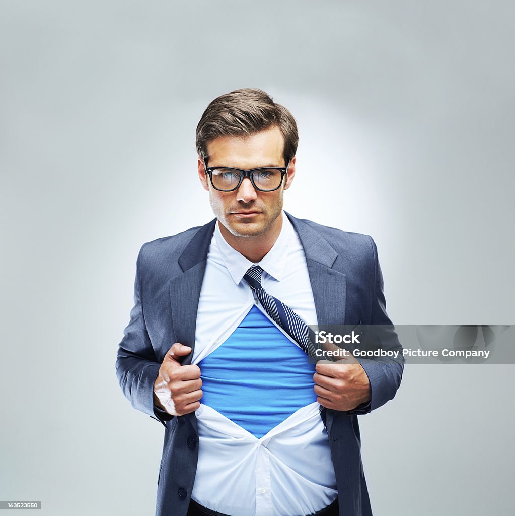 Super business practices A studio shot of a serious businessman ripping open his shirt and exposing a costume underneath Superhero Stock Photo