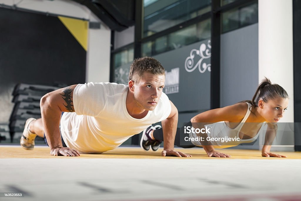 Young couple exercising at the fitness gym Woman in gym, with personal fitness trainer, exercising. Activity Stock Photo