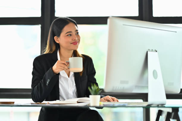 istock Attractive businesswoman holding coffee cup analyzing marketing data, statistics on computer screen 1635250120