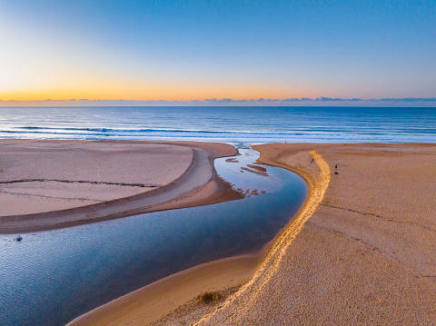 Aerial sunrise with the lagoon open to the sea at Wamberal Beach on the Central Coast, NSW, Australia.