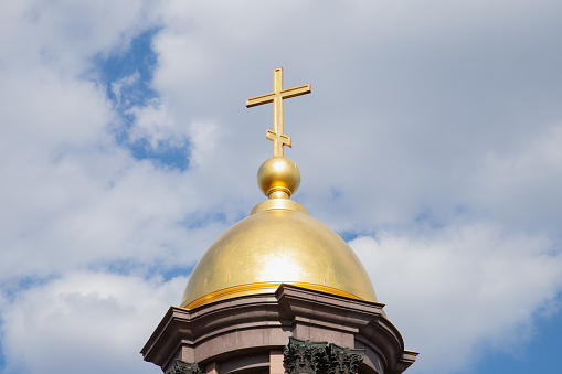 golden orthodox cross on gold dome on cloudy sky. close-up