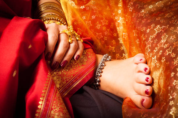 Focus on long sequined gown, high-heeled sandal, and man’s black pant leg and shoe as woman arrives for entertainment event.