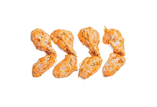 The raw, marinated chicken wings isolated on a white background.