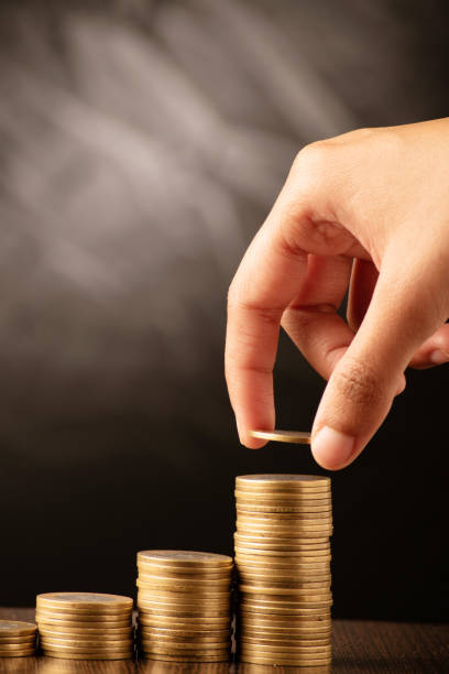 istock Closeup of hand putting money in coin stack 1635271040